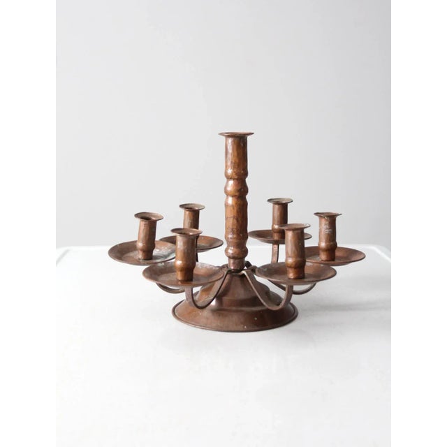 This is an antique copper candelabra featuring seven elegantly arranged candlesticks. The warm, natural patina of the...