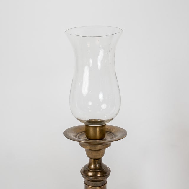 A refined pair of late 19th-century Continental European brass hurricane candlesticks, dating to circa 1890, complete with...
