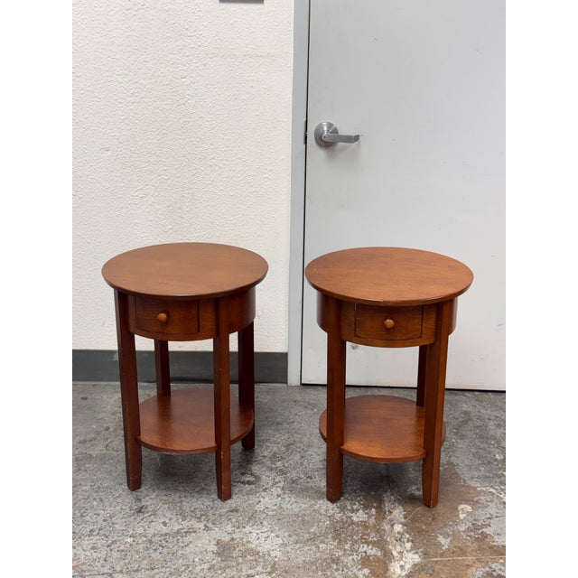 Design Plus Gallery presents a Pair of Julia Side Tables from Pottery Barn. Each nightstand has a round tabletop, a single...