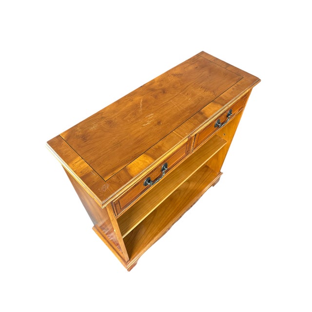 English-style sideboard in yew wood with two drawers and an open shelf. Features classic brass handles and a clean,...