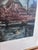 This original vintage landscape print, created around 1970, shows a peaceful river with trees, a boat and a cottage along...