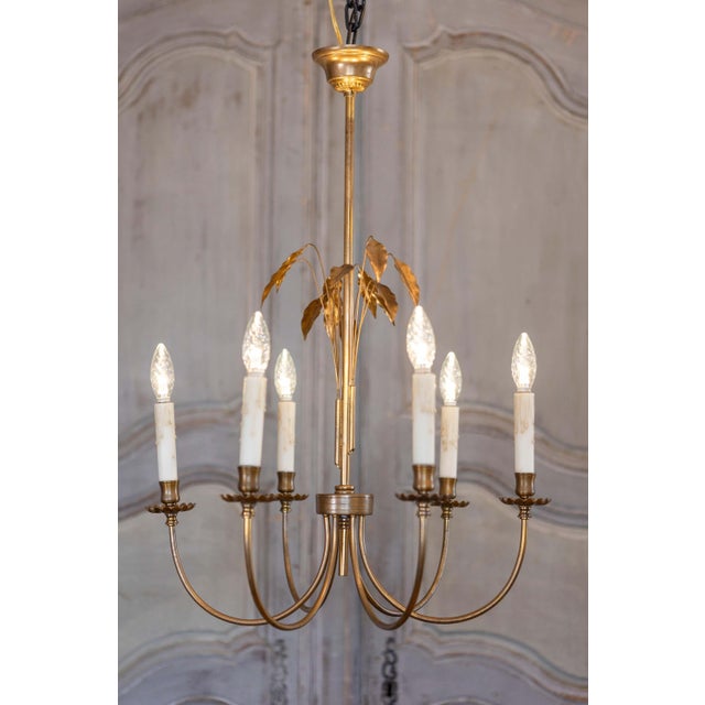 A French gilt metal six-light chandelier from the 20th century inspired by Maison Charles, with swoop arms and foliage...