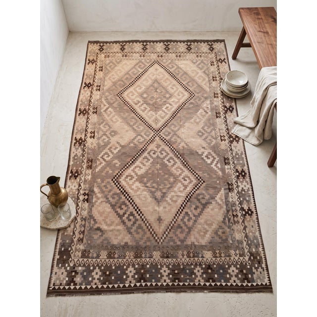 This vintage Afghan Maimana Ghalmori kilim is a large handwoven rug with a light beige center, warm brown borders, and...