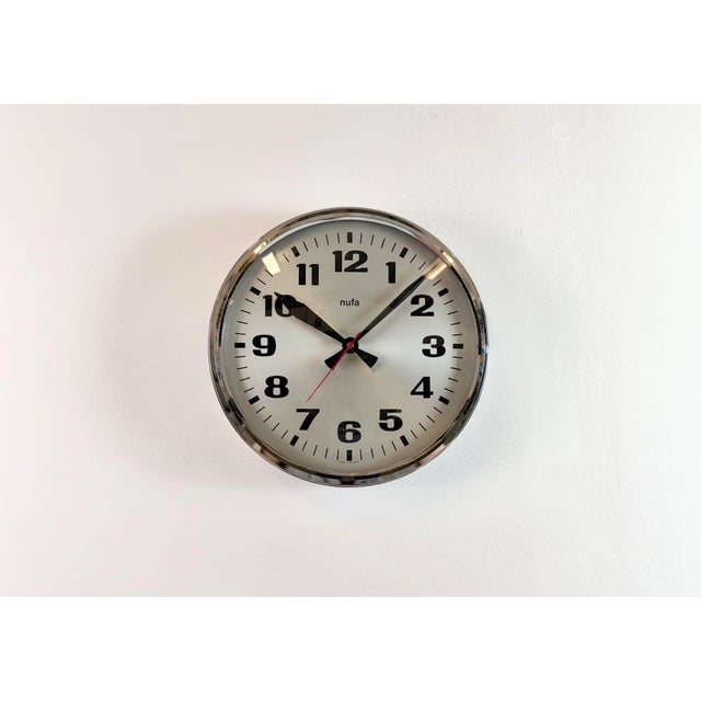 This wall clock was produced by NUFA in Germany during the 1960s. It features a silver chrome plated bakelite frame, a...