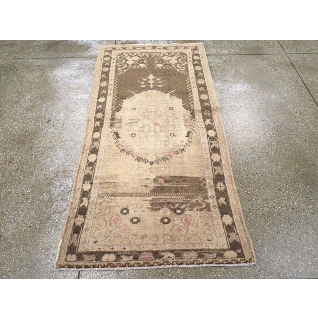 A vintage Turkish Oushak throw rug. The field strongly abrashes from medium-dark brown to beige n this narrow west...
