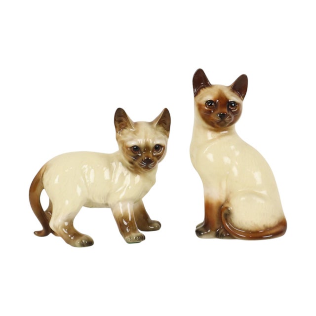 A vintage pair of Siamese cats made of glazed ceramic during the 1950s or 1960s, one is marked "Japan" on the bottom....
