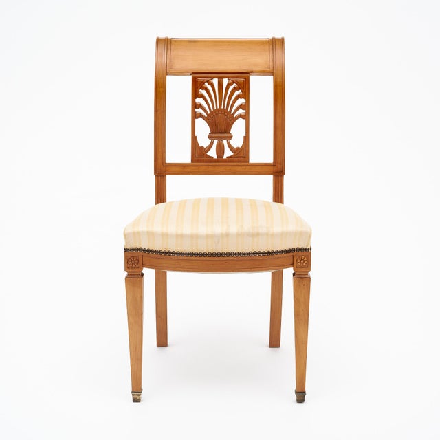 Directoire style antique French chairs made with solid wood construction that has been finished with a lustrous French...