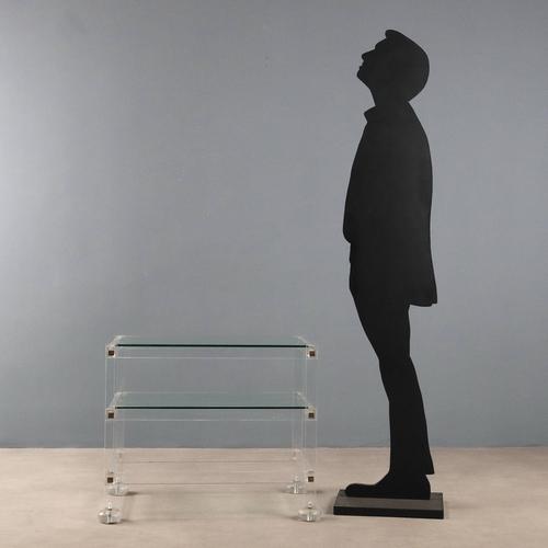 A three-tier table made of acrylic glass, with clear glass tops and brass details. One glass top is missing. This piece is...