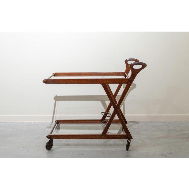Italian serving trolley on wheels made of ebonized beech wood and glass. It features two handles and a lightweight, two-...
