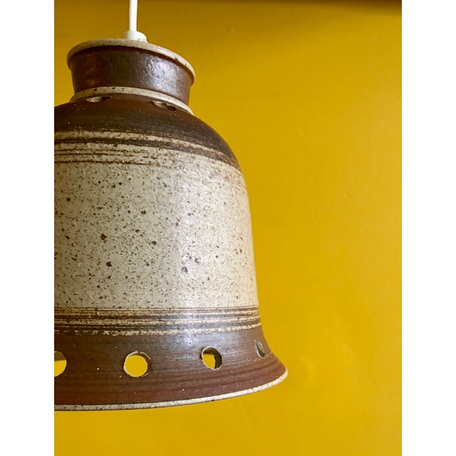 This vintage 1970s Danish ceramic pendant lamp features a textured, speckled beige and brown stoneware body with...