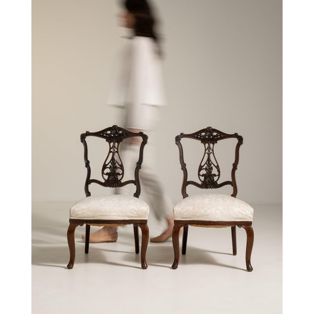 A decorative pair of Victorian chairs showcasing detailed carving and classic proportions. Victorian furniture often...