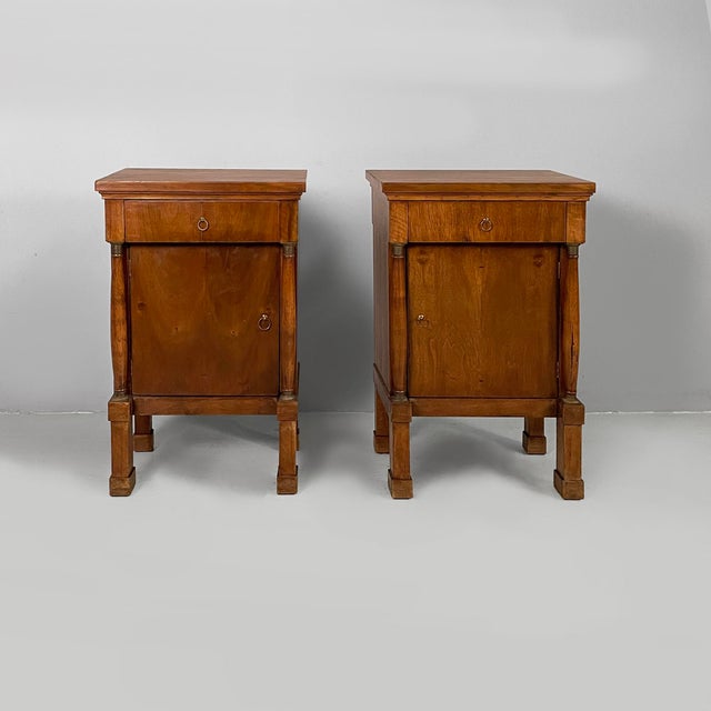 Italian Empire style bedside tables in wood, early 19th century Pair of wooden bedside tables. The front features a...