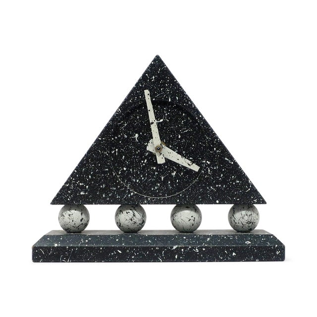 A stunning postmodern desk clock with dark gray rectangular base, round light gray supports, and dark gray triangular body...