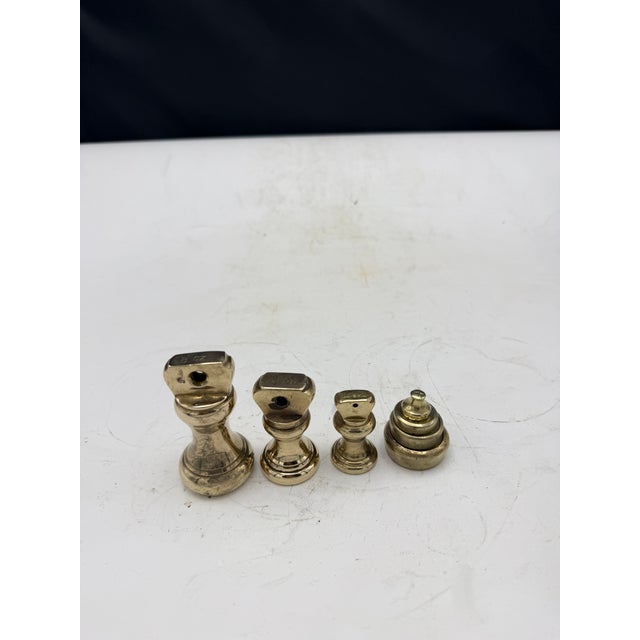 A set of 7 Antique solid brass scale weights. The set features three barbell weights and 4 disc weights. The barbell...