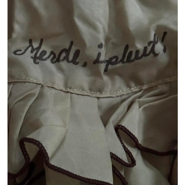 "Merde, il pleut!" — "Shit, it's raining!" A 1940s French umbrella with a ruffled edge, featuring the expressive...