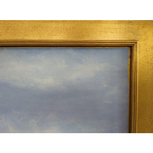 An evocative painting in a gold frame, showcasing a tranquil blend of blues and soft whites, capturing the serene expanse...