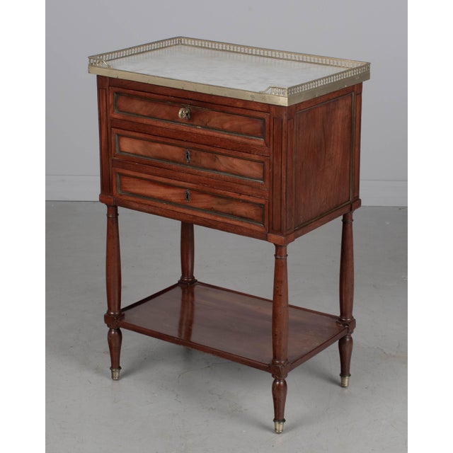 A 19th century French Louis XVI style marble top nightstand, or side table, made of veneers of mahogany with solid oak as...