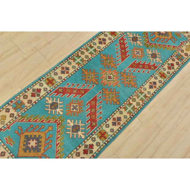A tribal Caucasian Kazak runner hand-knotted with fine wool on a cotton foundation. This rug features geometric motifs set...