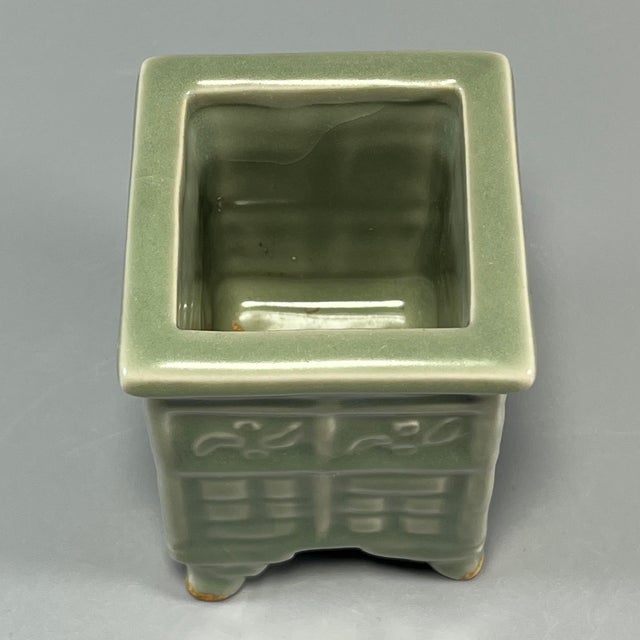 This vintage‑style square celadon censer stands on four sturdy feet. Its outer walls are decorated with delicate embossed...