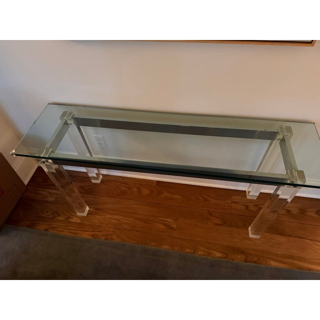 A clean-lined vintage console that pairs a sculptural Lucite base with a substantial glass top — the kind of transitional...