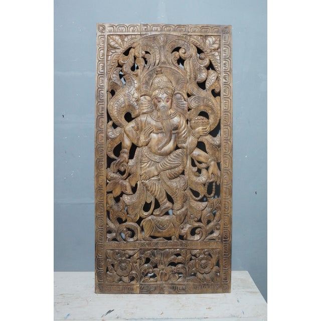 A striking hand-carved wall panel featuring Lord Ganesha, the beloved Hindu deity of wisdom and new beginnings, rendered...