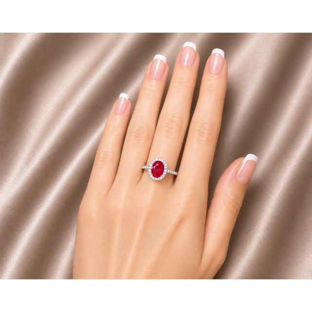 Elegant 14K white gold cocktail ring featuring one natural oval ruby nearly 1 carat surrounded by brilliant round diamonds...