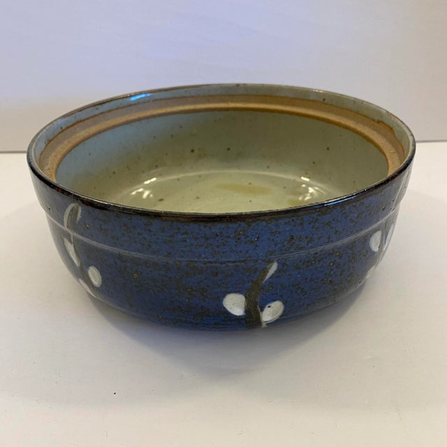A richly glazed vintage studio pottery bowl with a deep cobalt-blue exterior and loose, hand-painted botanical decoration...