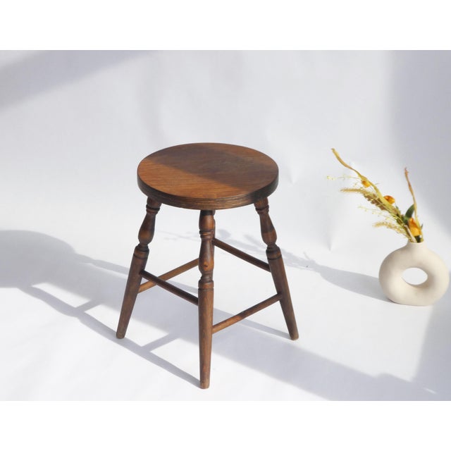 Antique round wooden stool made in England with nice carved legs. The plant stand is overall in good condition with traces...