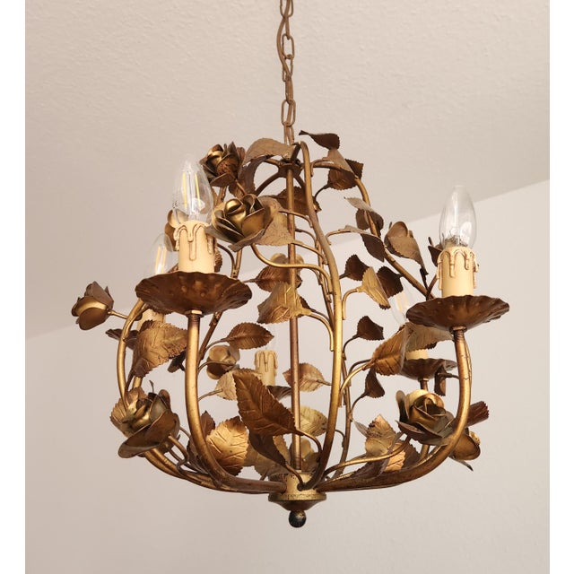 A highly decorative, gold-colored chandelier with rose and leaf embellishments. beautiful vintage chandelier in a floral...