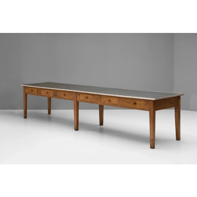 Double sided 12 drawer drapers / shop table in oak with leatherette covered top. Circa 1900.