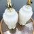 A glamorous pair of Hollywood Regency table lamps featuring sculptural white milk glass bodies with elegant scalloped...