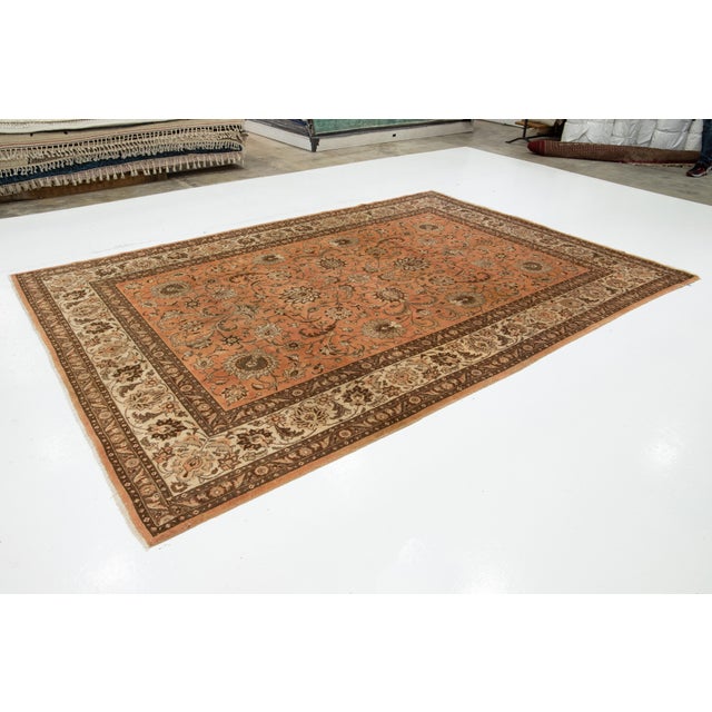 This Persian Tabriz wool rug is handcrafted with a classic all-over floral pattern. The peach background contrasts the...