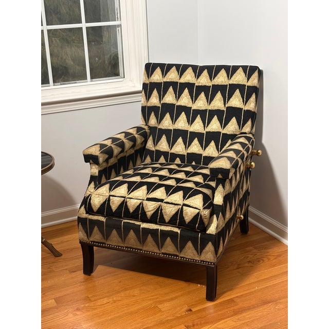 Bold Art Deco–inspired accent chair in black and gold geometric upholstery, featuring polished brass hardware and nailhead...