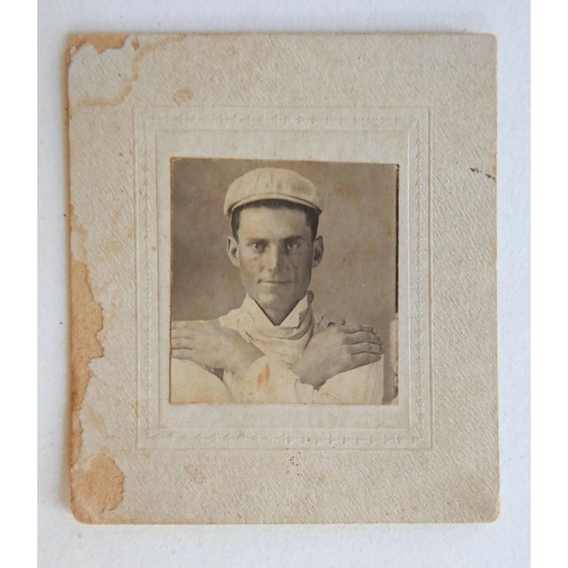Small circa 1900 photograph mounted on cream cardboard of a handsome man. His cap look like a bicyclist and he has his...