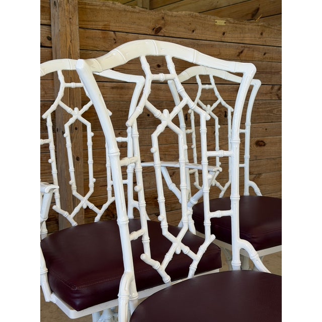 A fabulous set of four vintage faux bamboo swivel dining chairs featuring sculptural metal frames with intricate geometric...