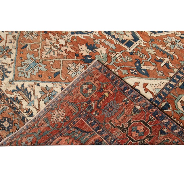 Beautiful antique Heriz hand-knotted wool rug with an orange rust color field. This Persian rug has dark blue and peach...