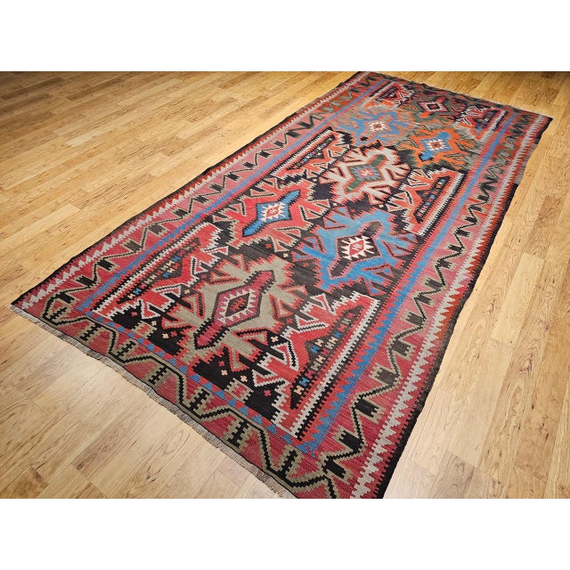 This early 20th-century Caucasian Kazak kilim from the Shirvan region of the Southern Caucasus is a vibrant example of...