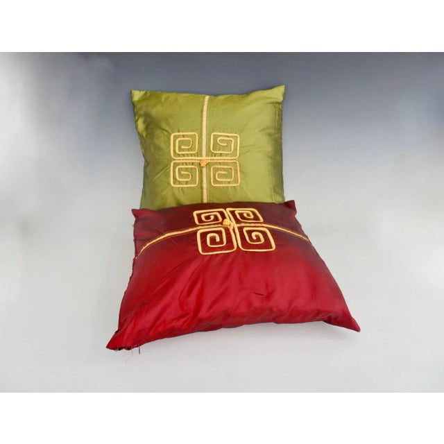 Pair of mid-20th century decorator pillows in the Hollywood Regency style of James Mont. Covered in ruby red and emerald...