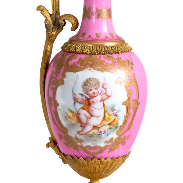Sevres Gilt Metal Mounted Pink Ground Porcelain Ewer, late 19th century, the body painted with panels of cupid at play,...