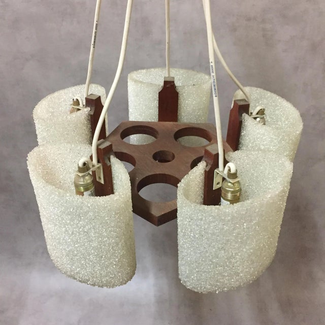 This Scandinavian round shaped pendant has a teak frame and five resin lampshades in acrylic glass from the 1970s....