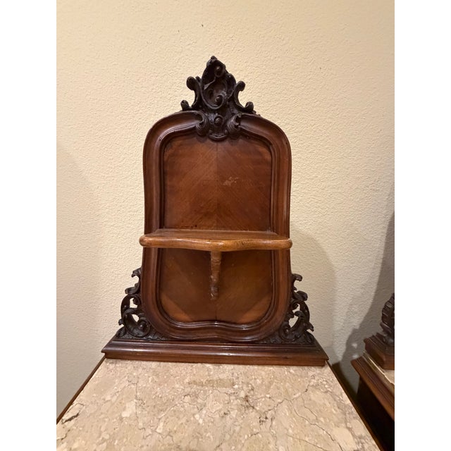 Elegant matched pair of antique French bedside cabinets featuring carved crest backs, marble tops, and cabriole legs. Each...