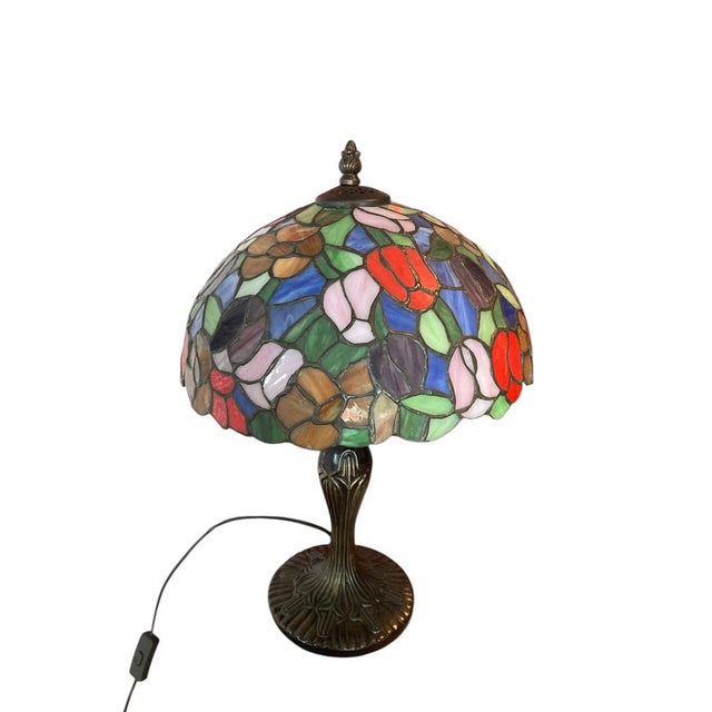 Tiffany Style Stained Glass Table Lamp characterized by its vibrant floral motifs and classic Art Nouveau aesthetic. The...