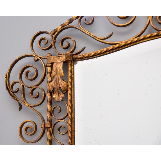 Found in Italy, this circa 1930s mirror has a gilt iron frame with a lot of deocrative scroll work and acanthus leaf...