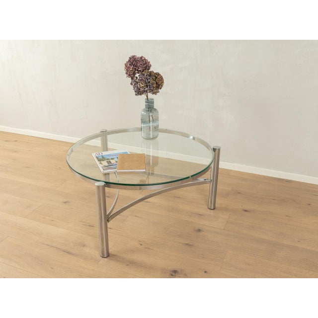 Classic coffee table from the 1990s. High-quality stainless steel frame with a glass table top. Small defect on the glass...