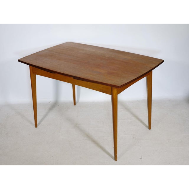 Extendable teak dining table, 1960s. Simple, minimalist design with a gently curved tabletop and slender, tapered legs....