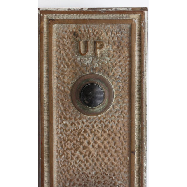 Reclaimed textured cast bronze elevator plate with black plastic "Up" and "Down" indicator buttons. Inscribed on the back...
