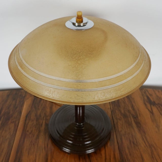 An art deco table lamp with brown bakelite stem and circular stepped bakelite base. Original tinted bakelite shade with a...