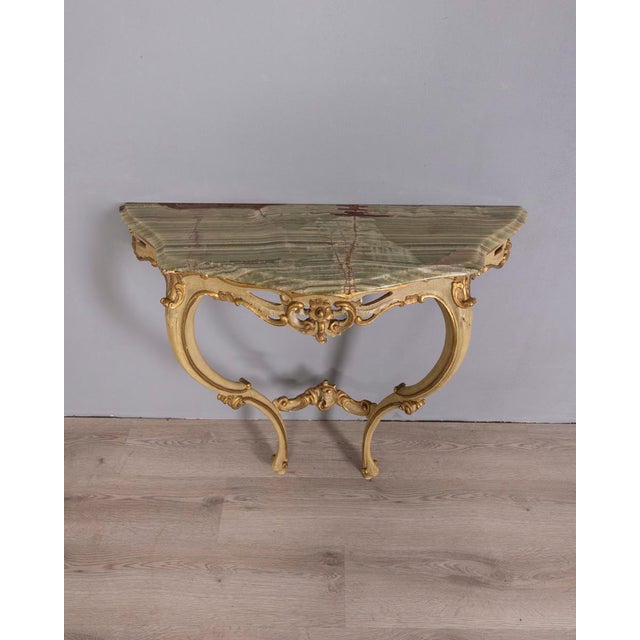 Wall console table with gold and cream carved wooden structure, onyx stone top, Baroque style, early 20th century.