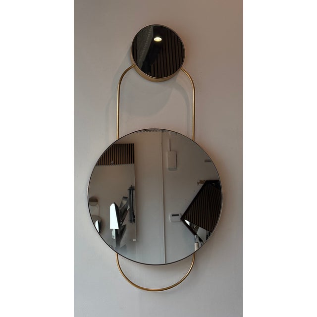 Elegant wall mirror with a modern design, combining metal and glass in a refined gold finish. Its double circular form,...