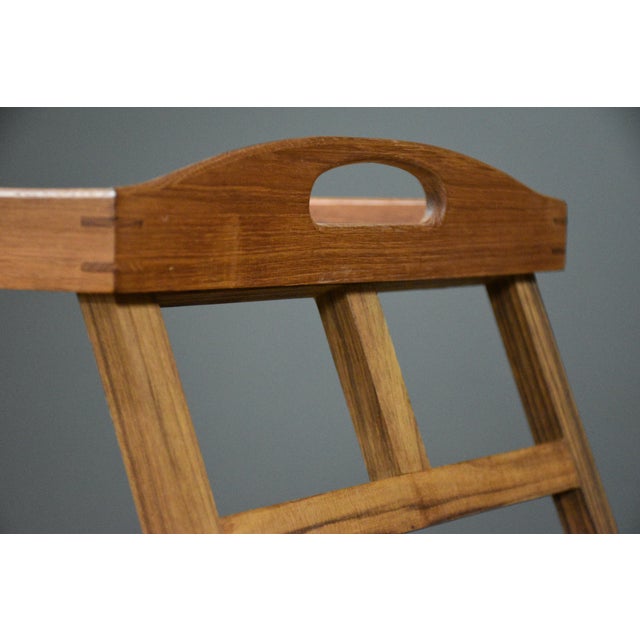 A mid century modern solid teak serving tray typical of Danish style. Tray has two self storing legs that fold out to act...